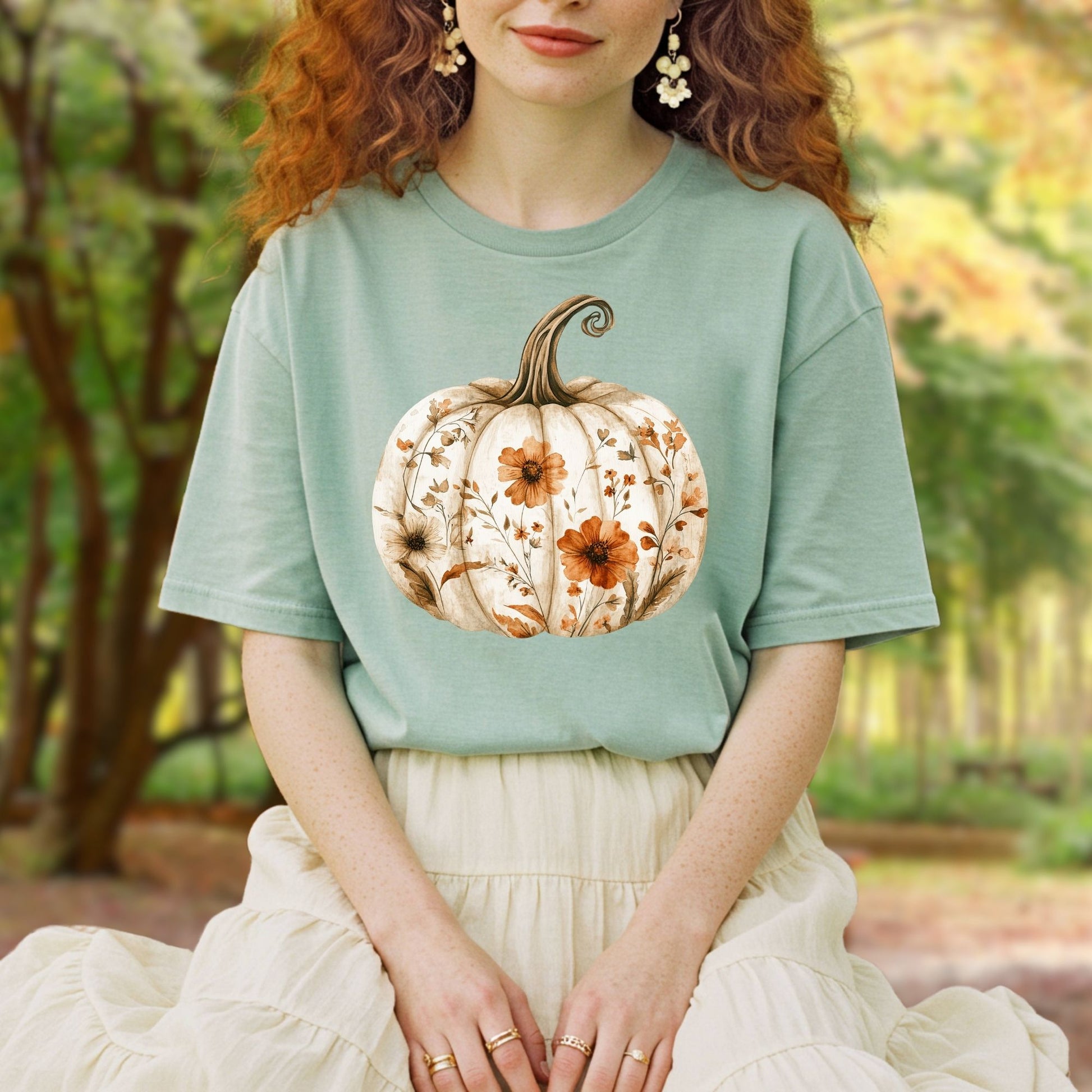 Relaxed-fit, garment-dyed sage green t-shirt with a white pumpkin blooming with orange and brown wildflowers.