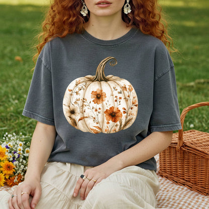 Garment-dyed charcoal t-shirt with a white pumpkin blooming with delicate wildflowers, worn by a person on a picnic blanket.