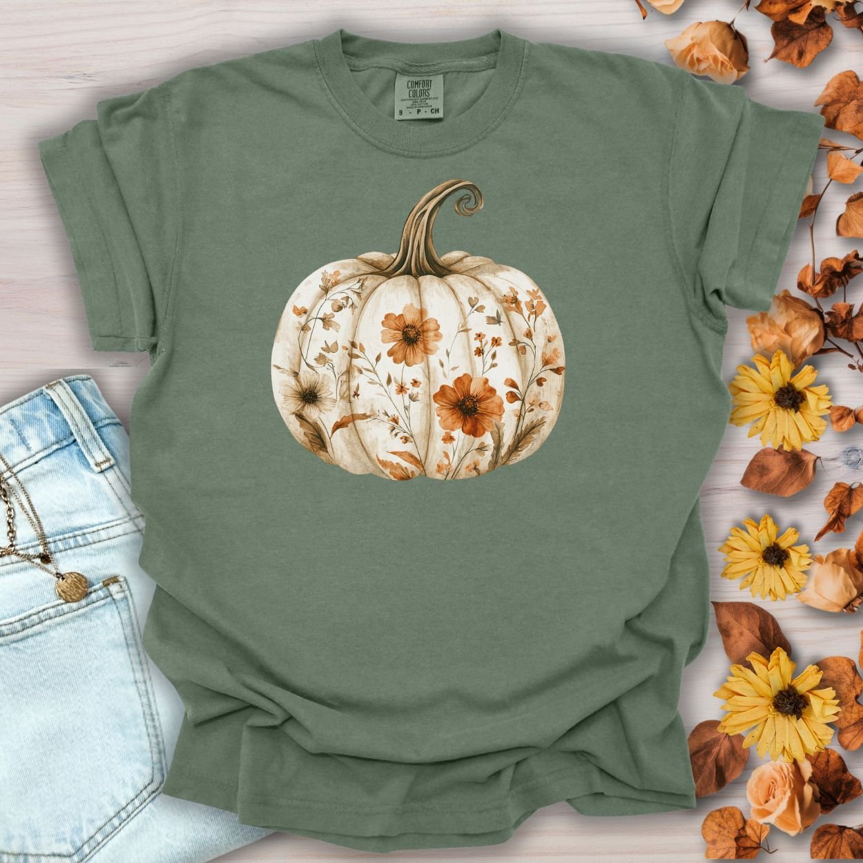 Moss green garment-dyed t-shirt with a white pumpkin blooming with orange and brown wildflowers.
