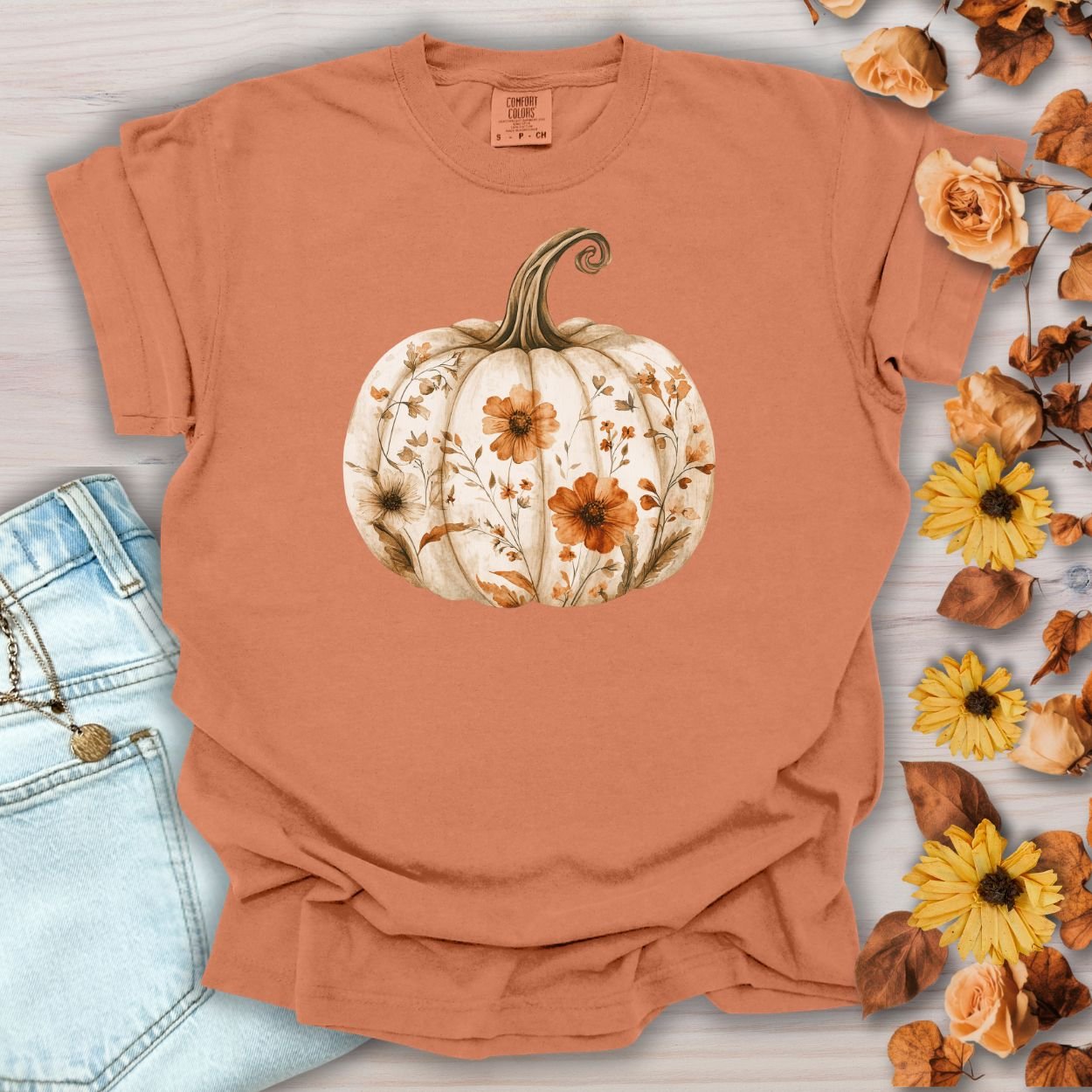 Yam-colored, relaxed-fit cotton t-shirt with a white pumpkin blooming with wildflowers.