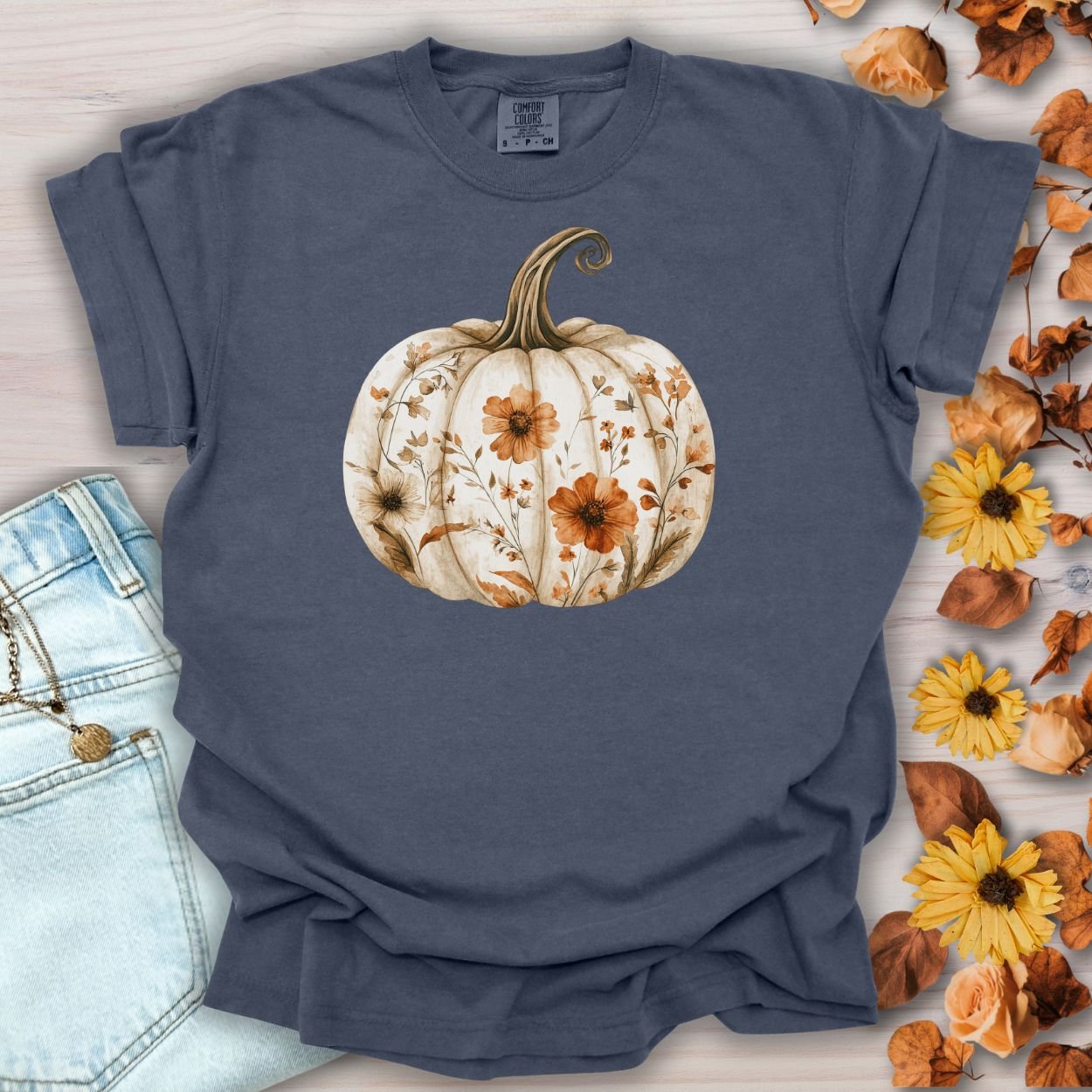 Denim garment-dyed t-shirt with a white pumpkin blooming with delicate wildflowers in warm, earthy tones.