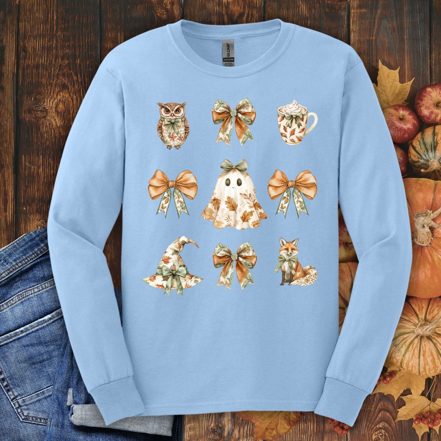 Light blue long sleeve cotton tee with a boho Halloween design: ghost, witch hat, fox, owl, bows, and mug.
