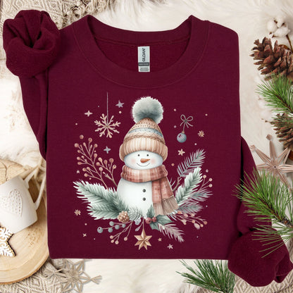 Maroon Gildan crewneck sweatshirt with a boho watercolor snowman, evergreen sprigs, and ornaments.