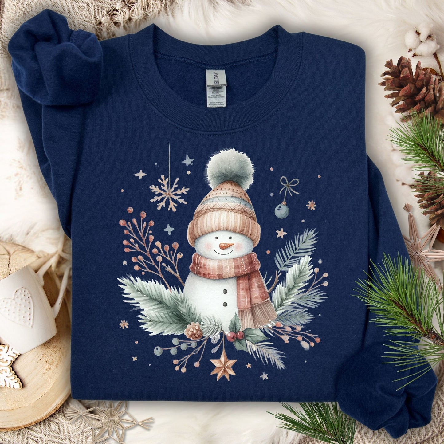 Navy S crewneck sweatshirt with boho watercolor snowman, flannel scarf, hat, and evergreen sprigs.