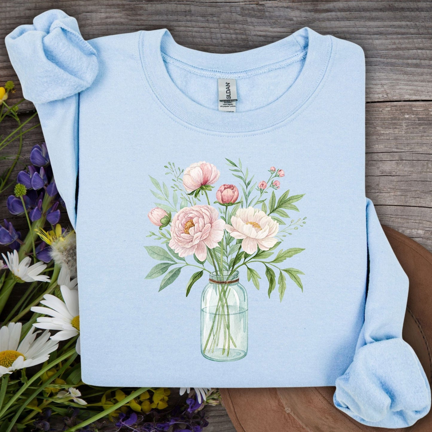 Light blue sweatshirt with botanical peony arrangement in glass jar design.