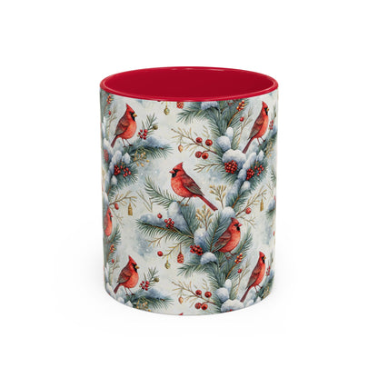 White ceramic mug with red interior and handle, featuring watercolor cardinals on snowy evergreen branches.