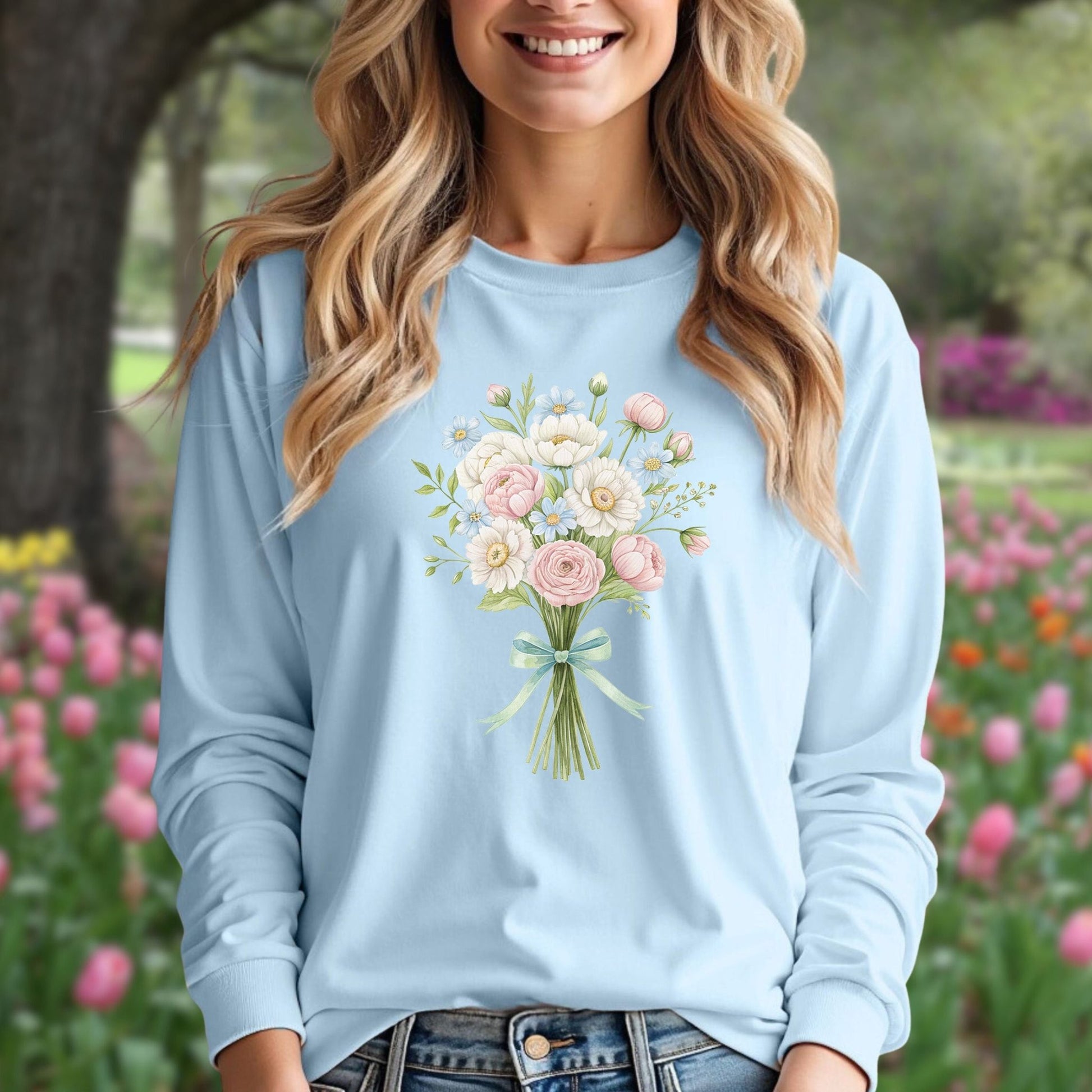Woman in light blue long-sleeve tee with a cheerful botanical bouquet of pink and white flowers.