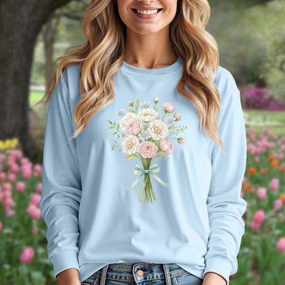 Woman in light blue long-sleeve tee with a cheerful botanical bouquet of pink and white flowers.