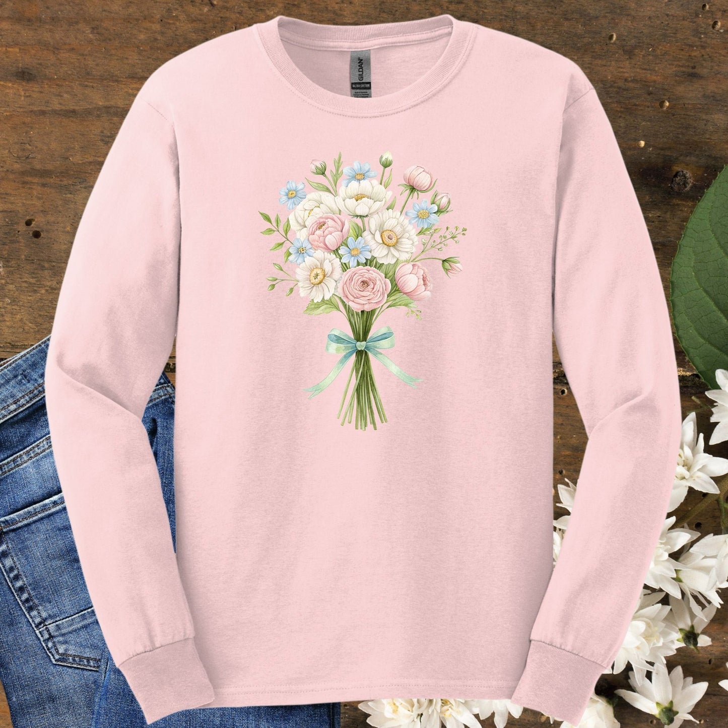 Light pink long sleeve tee with a cheerful botanical bouquet of dahlias, daisies, ranunculus, and roses tied with a ribbon.