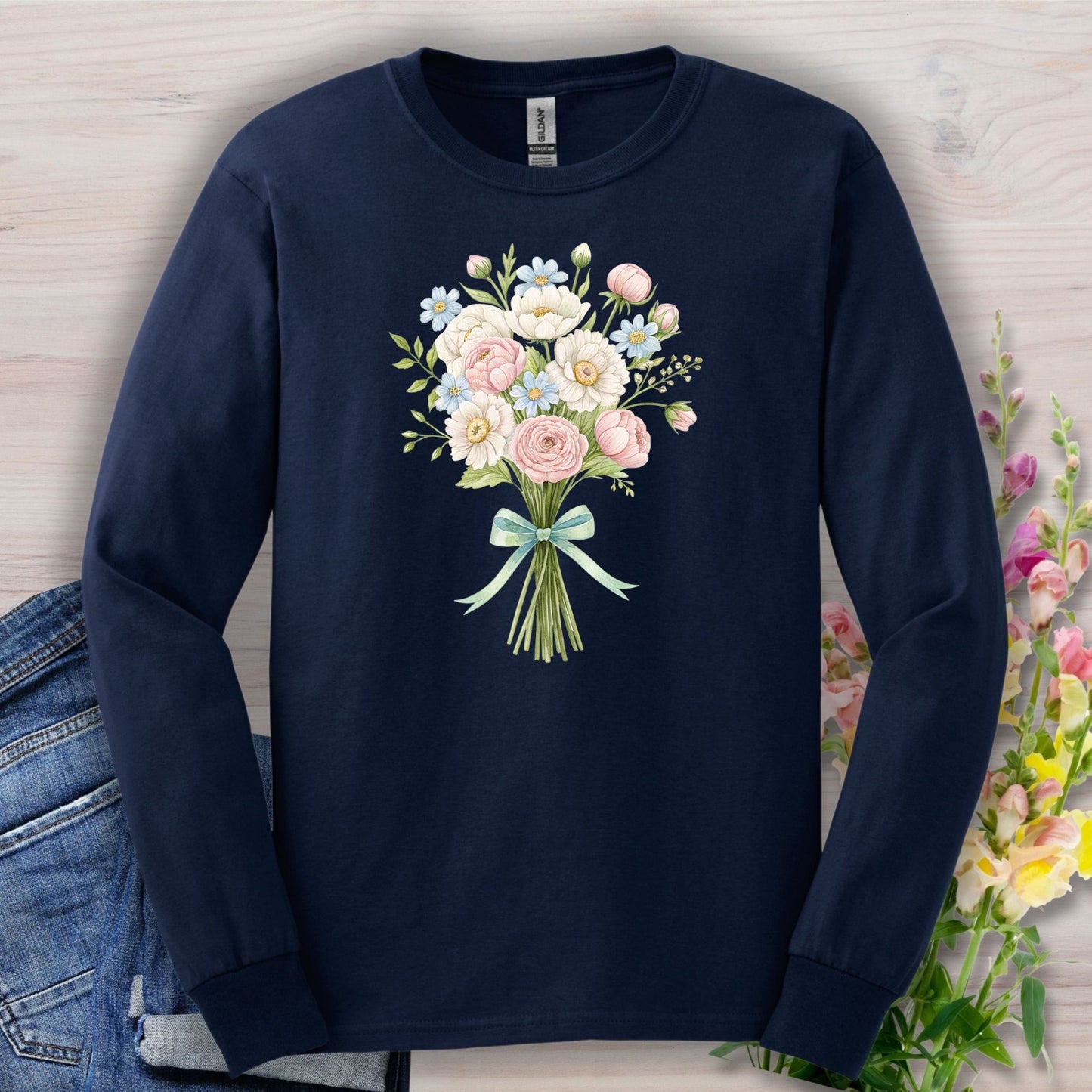 Navy long sleeve tee with a cheerful botanical bouquet of pink, white, and blue flowers tied with a green ribbon.