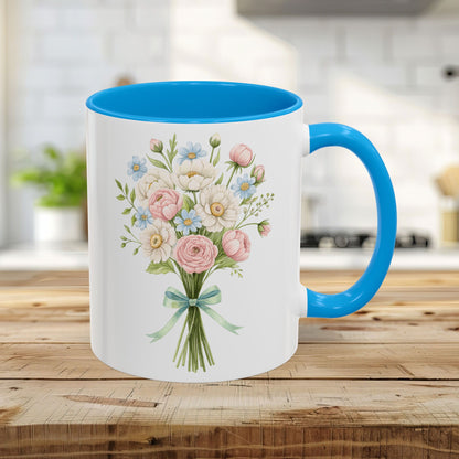 White ceramic 11oz mug with a cheerful pastel floral bouquet, light blue interior, and C-shaped handle.