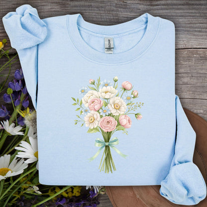 Light blue sweatshirt with a botanical illustration of pink and white flowers tied with a green ribbon.