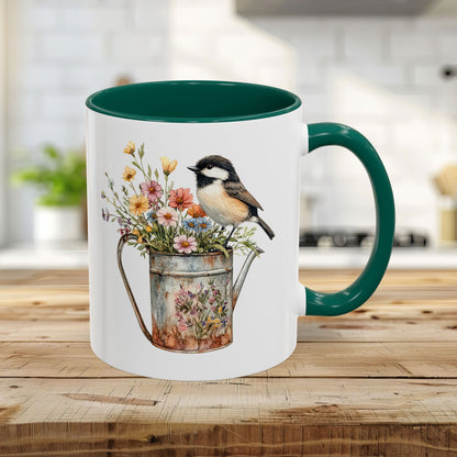 White ceramic 11oz mug with green handle and interior, featuring a watercolor chickadee on a floral watering can.