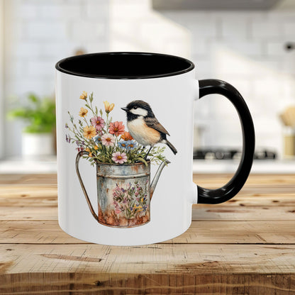 White ceramic mug with black interior and handle, featuring a watercolor chickadee on a floral watering can.