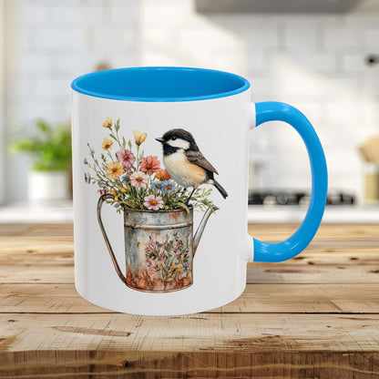 White ceramic 11oz mug with a light blue interior and handle, featuring a chickadee on a floral watering can.