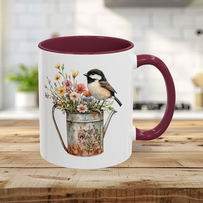 Glossy white ceramic 11oz mug with maroon interior/handle, featuring a chickadee on a floral watering can.