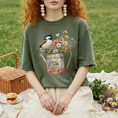 Garment-dyed olive green t-shirt with a chickadee perched on a floral watering can design.