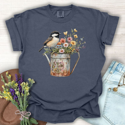 Garment-dyed navy t-shirt with a chickadee perched on a rustic watering can filled with wildflowers.