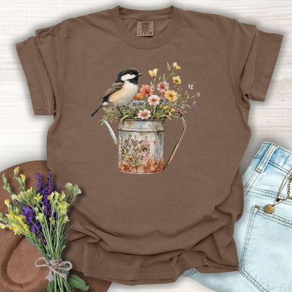 Espresso S t-shirt with a chickadee perched on a weathered watering can brimming with wildflowers.