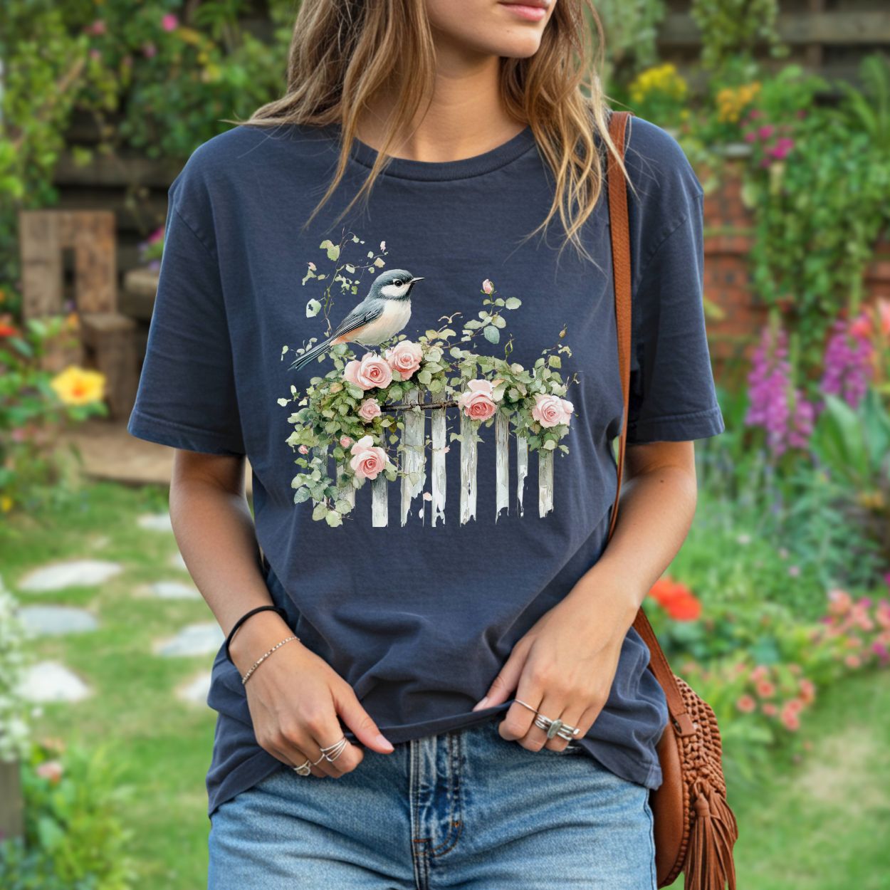 Garment-dyed navy t-shirt with a watercolor chickadee on a rose-covered white picket fence.