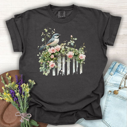Pepper S-size garment-dyed cotton t-shirt with a watercolor chickadee on a rose-covered white fence.