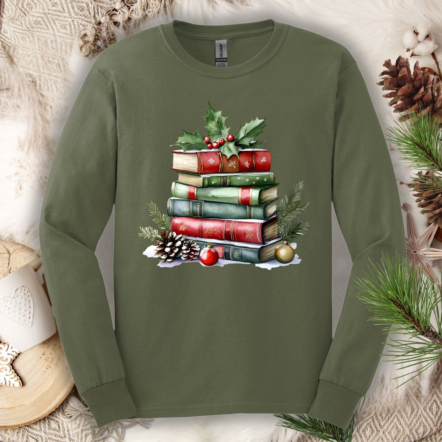 Military Green long sleeve tee with a watercolor Christmas book stack, holly, pinecones, and ornaments.