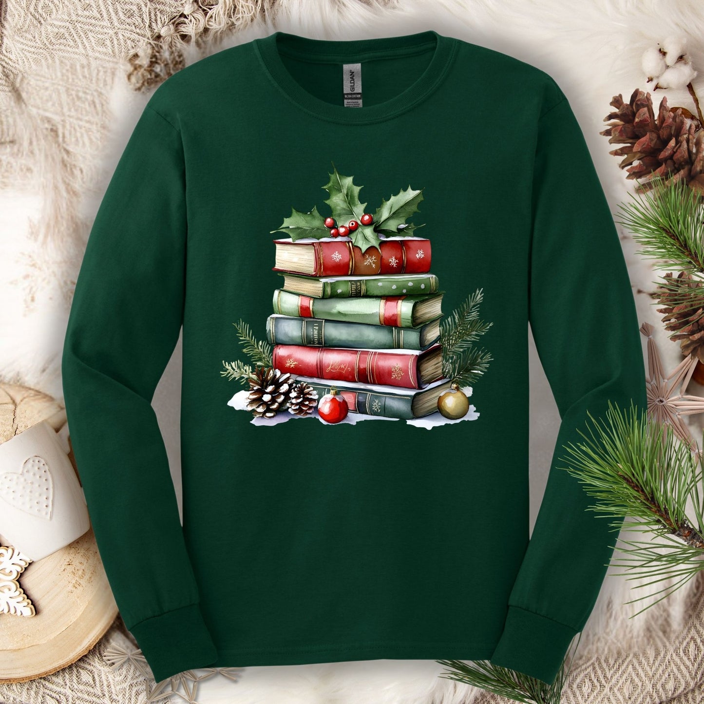 Forest green long sleeve tee with a vintage watercolor Christmas book stack, holly, pinecones, and ornaments.