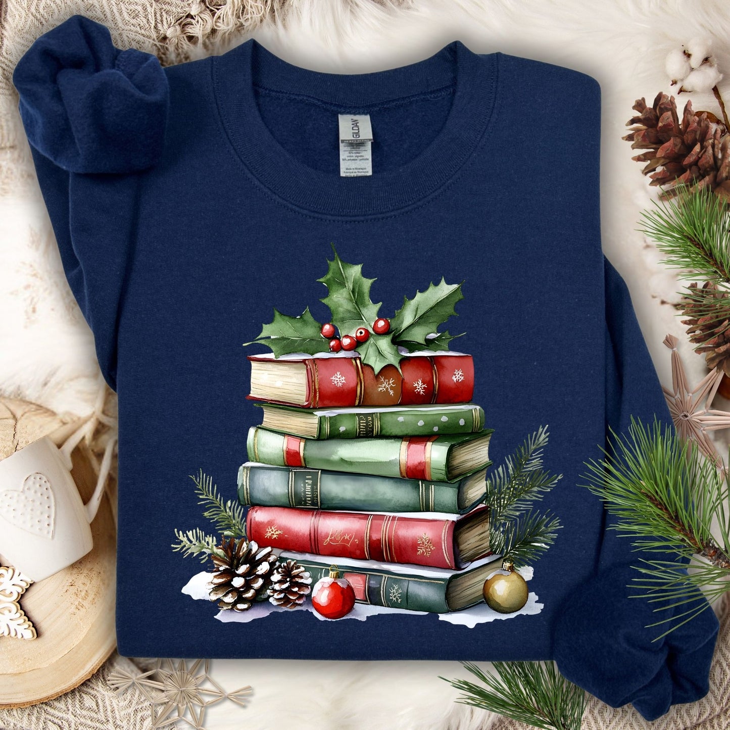 Navy Gildan sweatshirt with a watercolor stack of Christmas books, holly, pinecones, and ornaments.