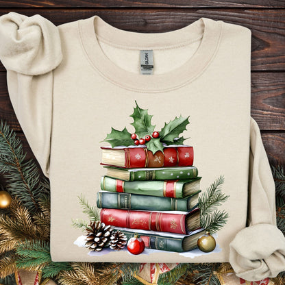 Sand Gildan sweatshirt with a watercolor Christmas book stack, holly, pinecones, and ornaments.