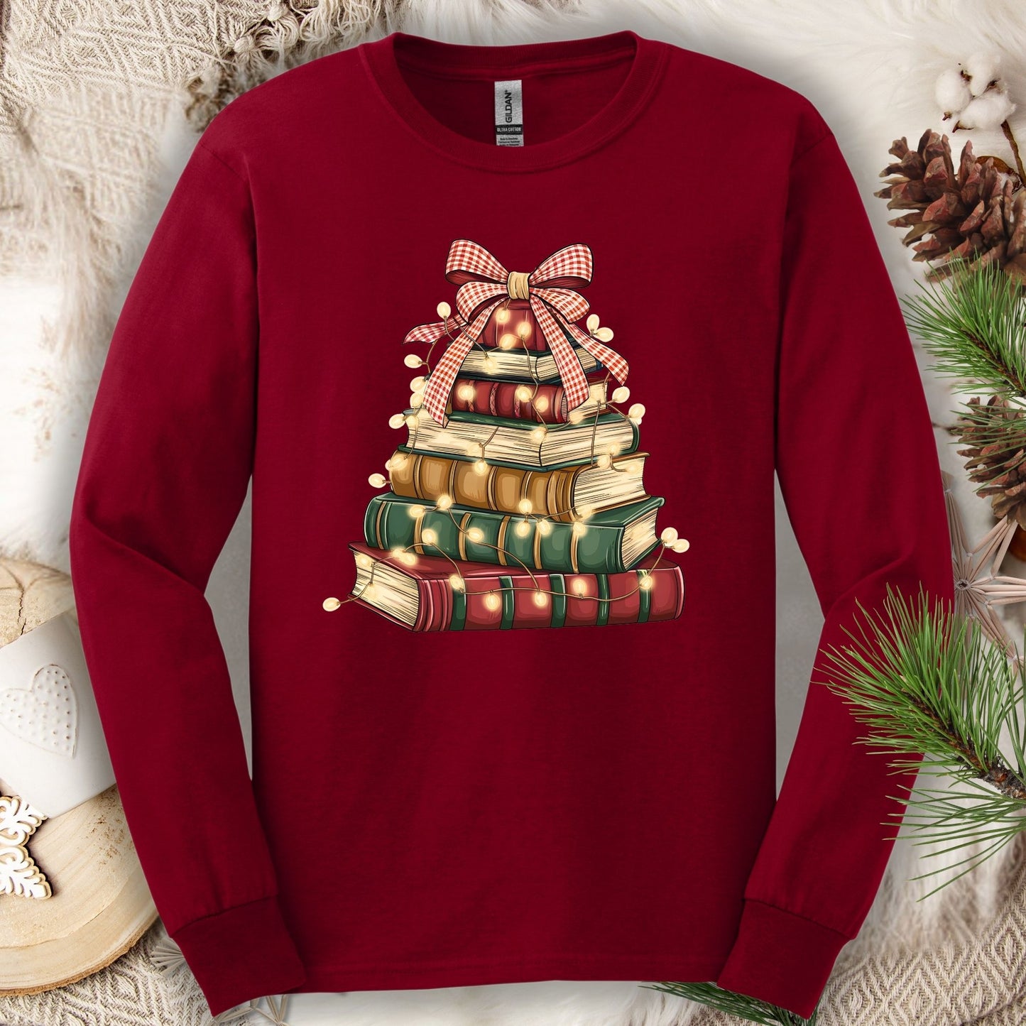 Cardinal Red long sleeve tee with a watercolor Christmas book tree design, string lights, and a plaid bow.