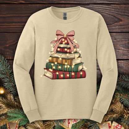 Sand long sleeve tee with a watercolor Christmas book tree design, festive bow, and string lights.