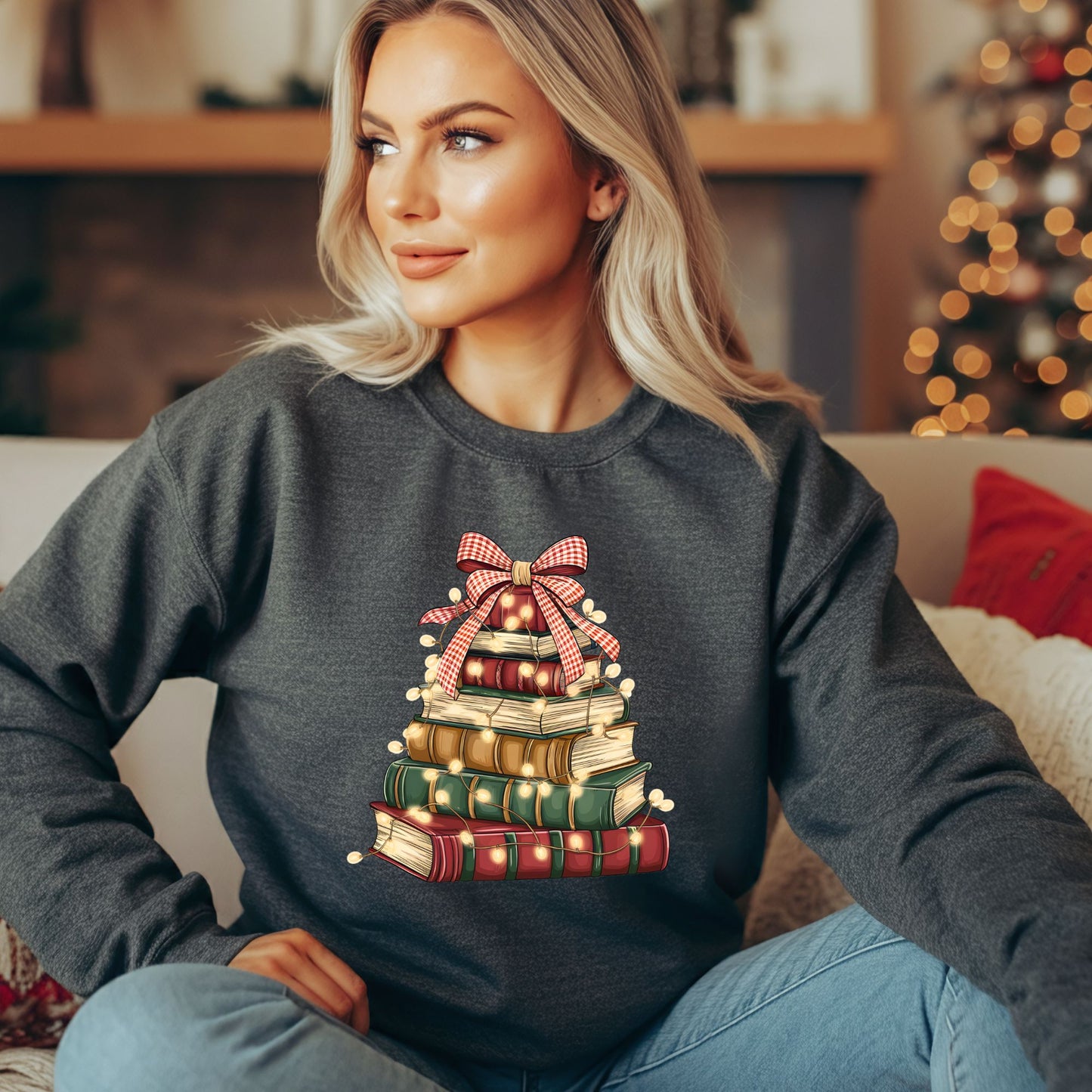 Woman in a charcoal gray fleece sweatshirt with a vintage book Christmas tree design and twinkle lights.
