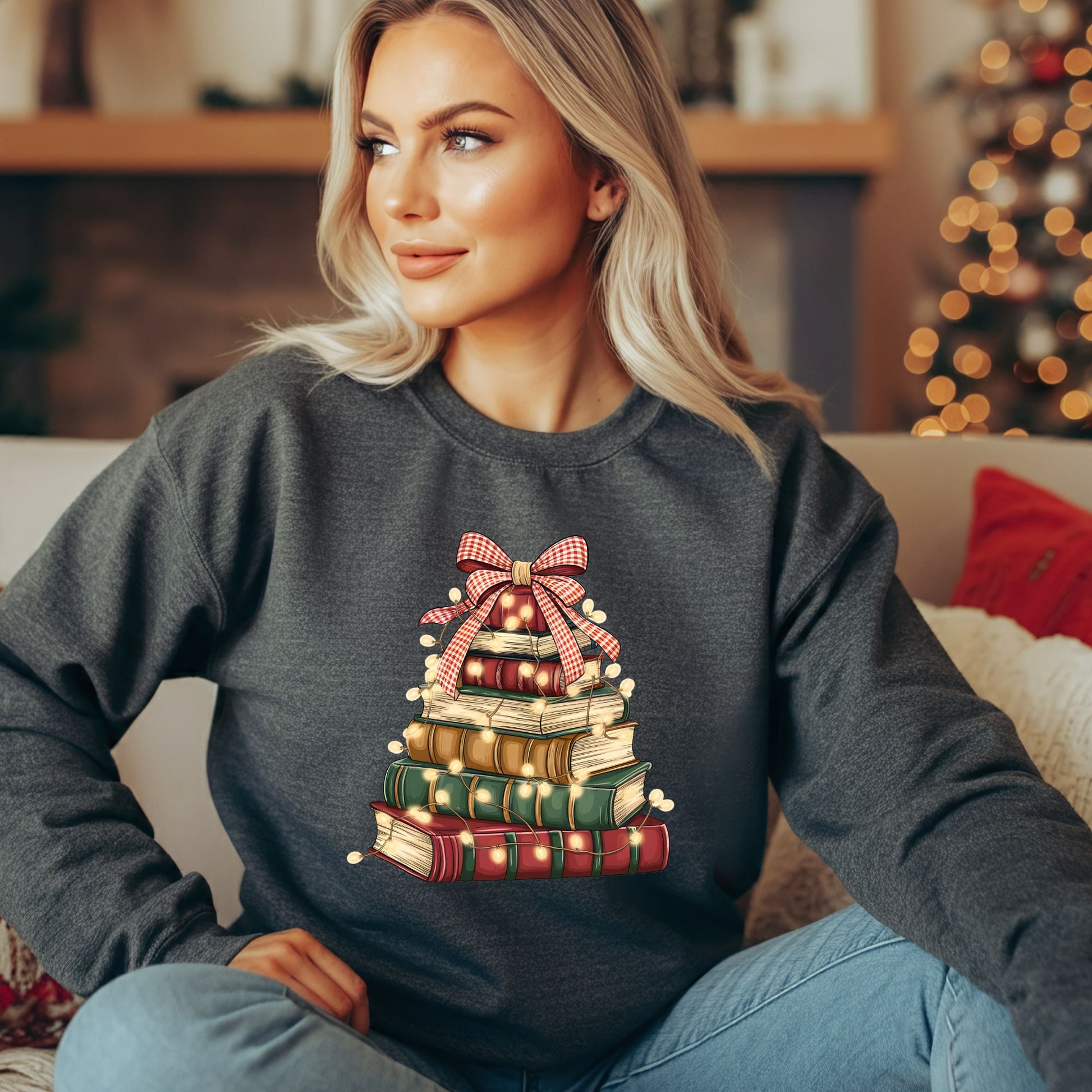 Woman in a charcoal gray fleece sweatshirt with a vintage book Christmas tree design and twinkle lights.