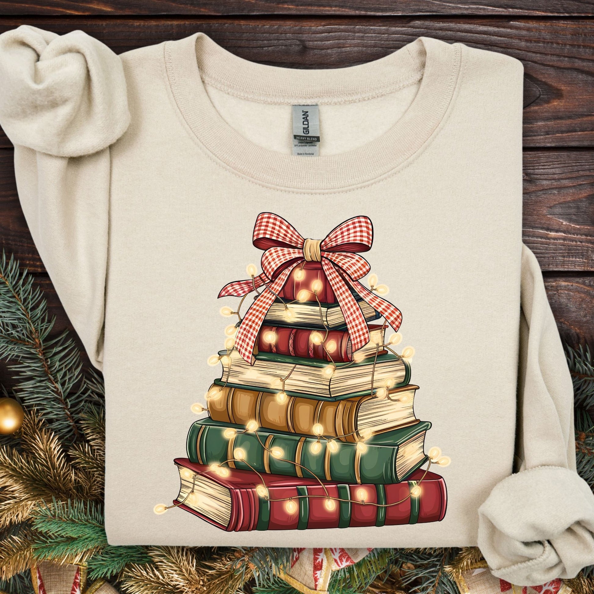 Sand sweatshirt with a vintage book tree design, red plaid bow, and glowing Christmas lights.