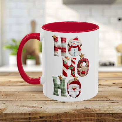 White ceramic Christmas mug with red interior and handle, featuring "Ho Ho Ho" in plaid, candy-cane, and woodland textures with snowmen, Santa, and reindeer.