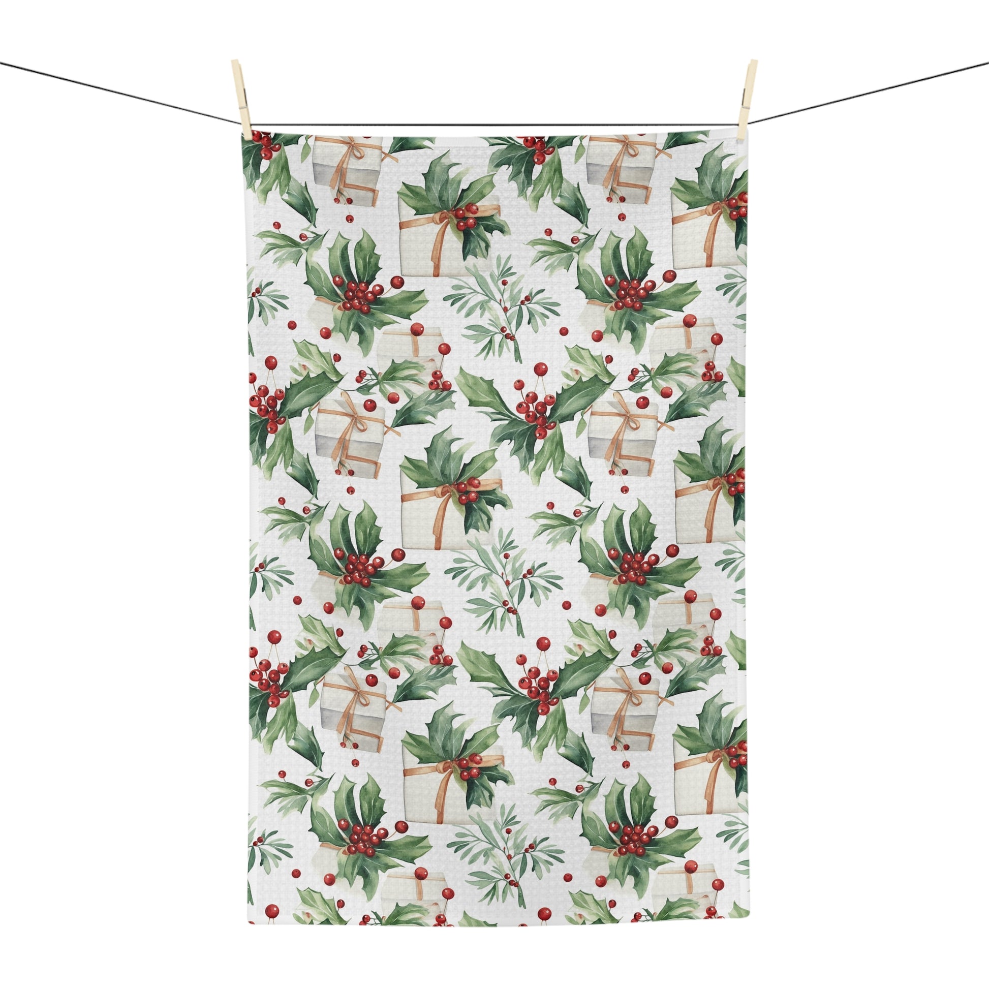 Microfiber tea towel with watercolor holly, red berries, and wrapped gifts, hanging on a clothesline.