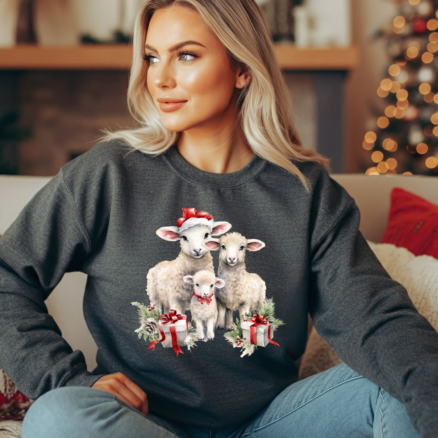 Charcoal crewneck sweatshirt with three watercolor lambs in Santa hats and gifts, worn by a blonde woman.