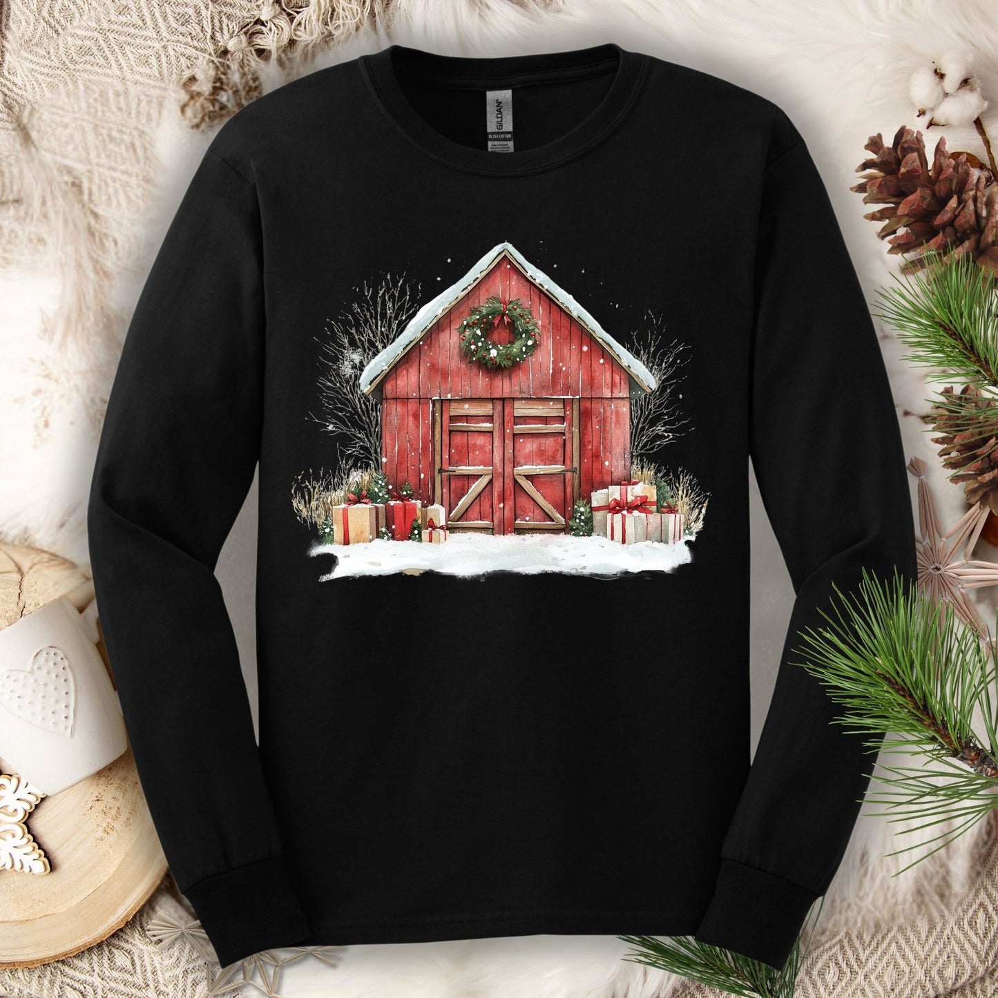 Black long sleeve tee with a watercolor red barn, snow, gifts, and evergreen wreath design.