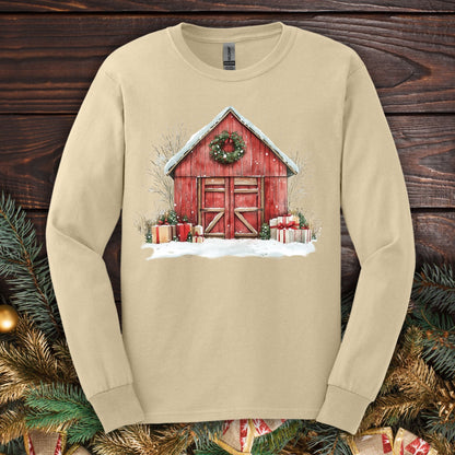 Sand long sleeve tee with a watercolor red barn, snow, gifts, and a Christmas wreath.