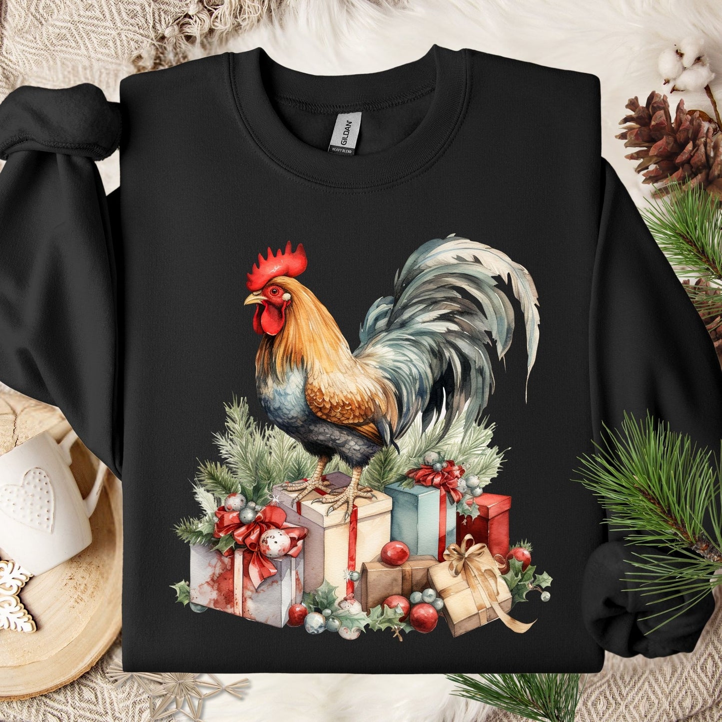 Black Gildan sweatshirt with a colorful watercolor rooster standing on Christmas gifts and pine boughs.