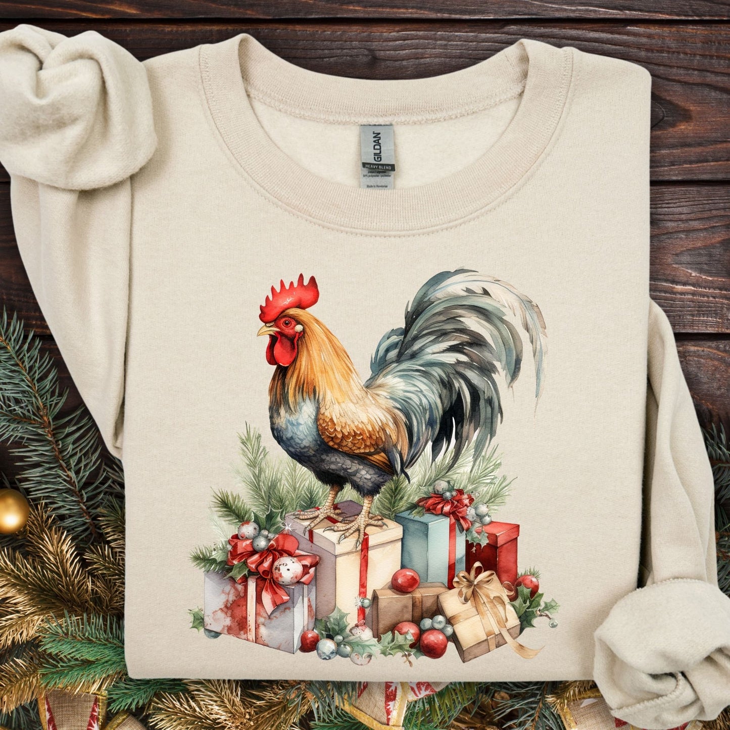 Sand Gildan sweatshirt with a watercolor Christmas rooster on gifts and pine branches.