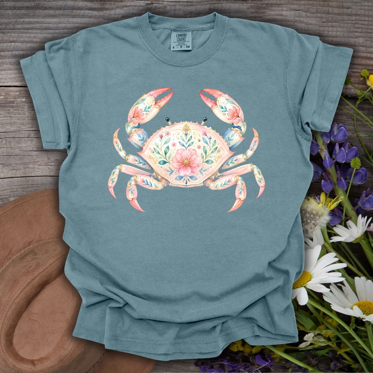 Ice Blue S t-shirt with a watercolor floral crab design, on a rustic wood background with wildflowers.