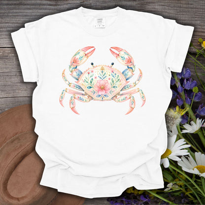 White S-size t-shirt with a watercolor floral crab design, on a wooden surface with flowers.