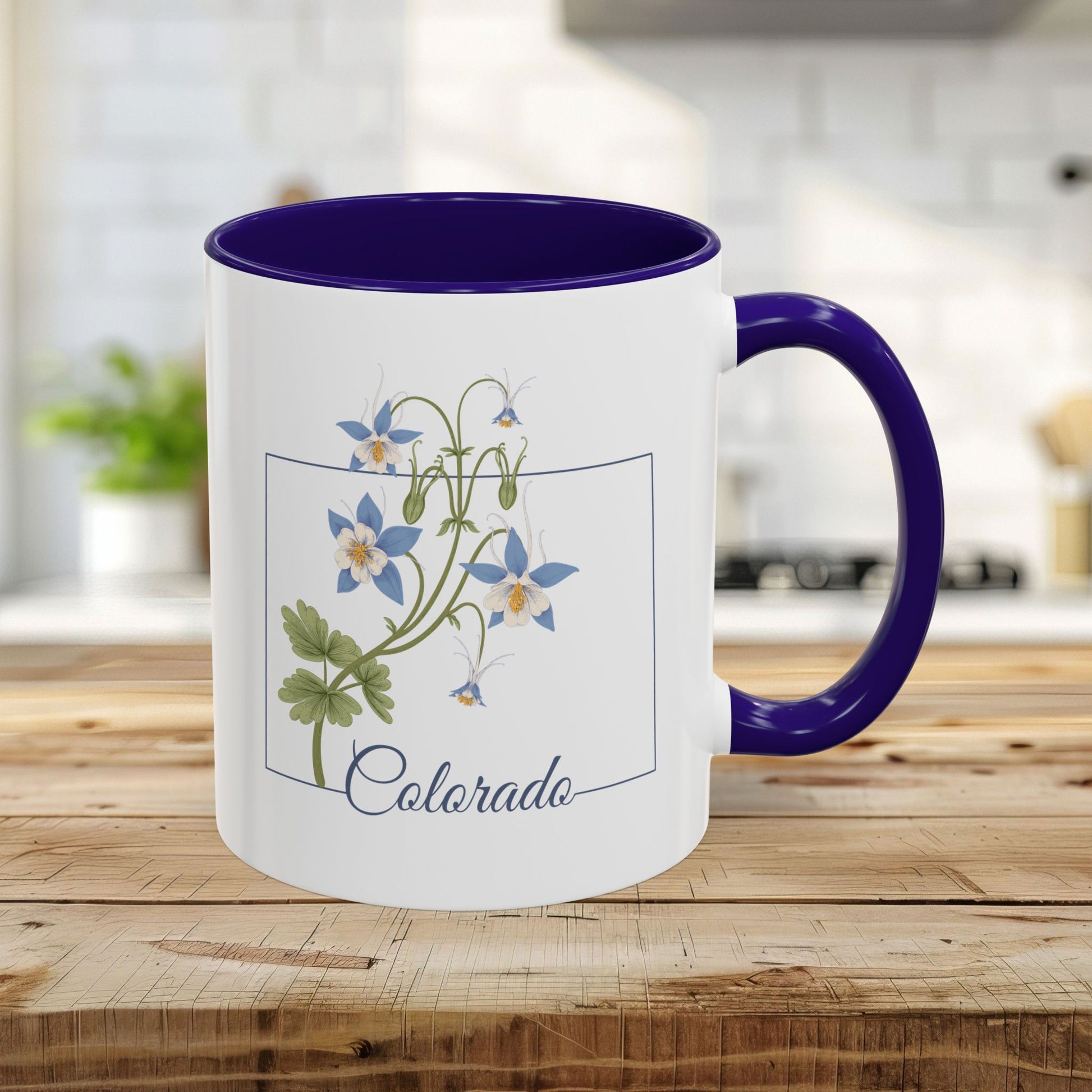 White 11oz ceramic mug with a blue interior and handle, featuring a framed Rocky Mountain Columbine watercolor print and "Colorado" script.