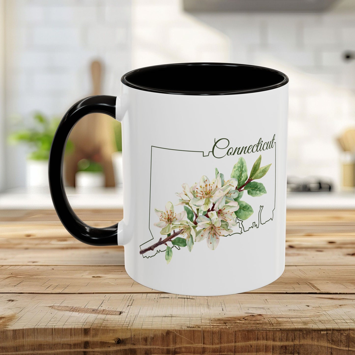 White ceramic mug with black handle and interior, featuring a watercolor Mountain Laurel bloom over a Connecticut outline.