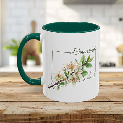 White ceramic mug with green interior and handle, featuring a watercolor Mountain Laurel bloom over a Connecticut outline.