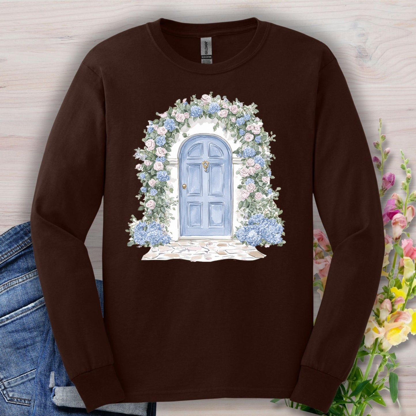 Dark Chocolate long-sleeve tee with a watercolor blue cottage door and pink and blue hydrangeas.
