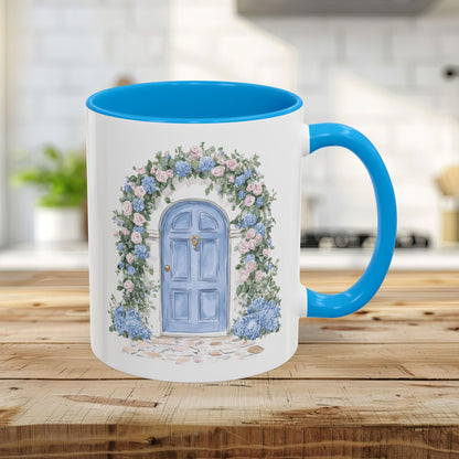 11oz ceramic mug with a light blue interior and handle, featuring a hand-painted blue doorway with roses and hydrangeas.