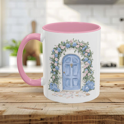 White ceramic mug with pink interior and handle, featuring a watercolor blue doorway framed by pink roses and blue hydrangeas.