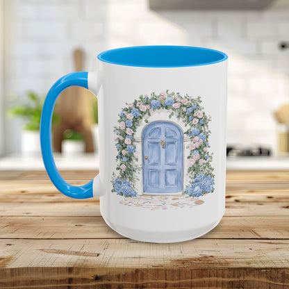 White ceramic mug with blue handle and interior, featuring a hand-painted blue cottage door framed by pink and blue hydrangeas.